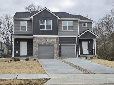 A grey house with two garages and a driveway.